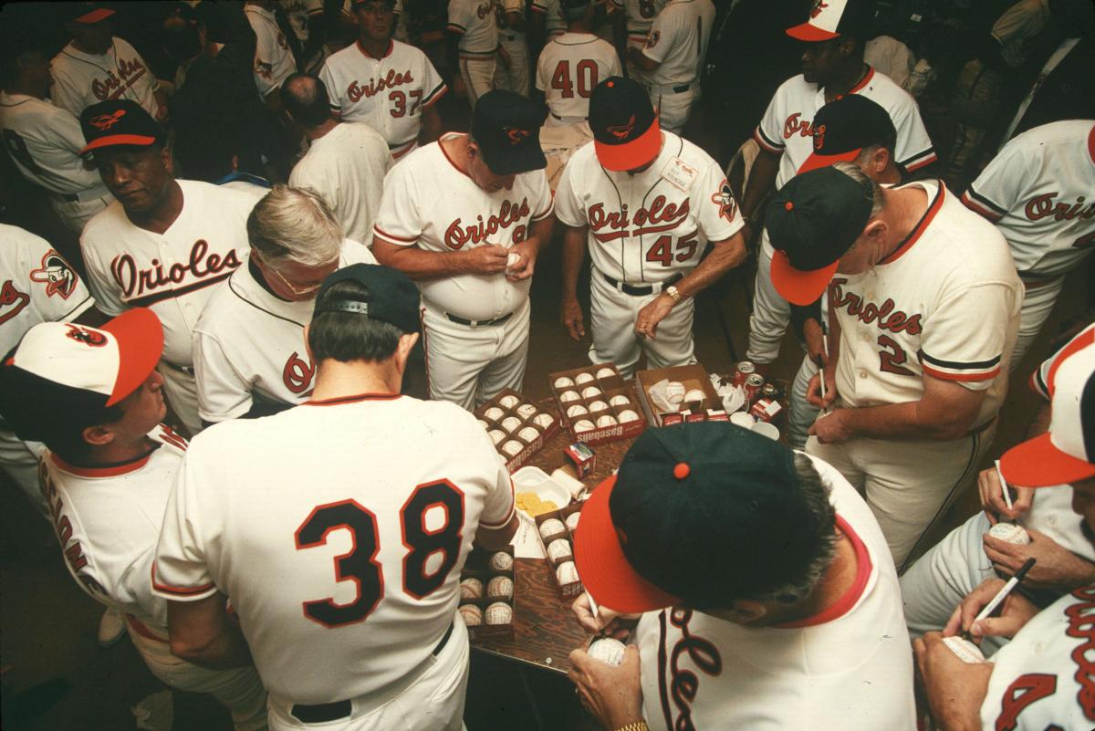 Retired Orioles players sign baseballs in the clubhouse