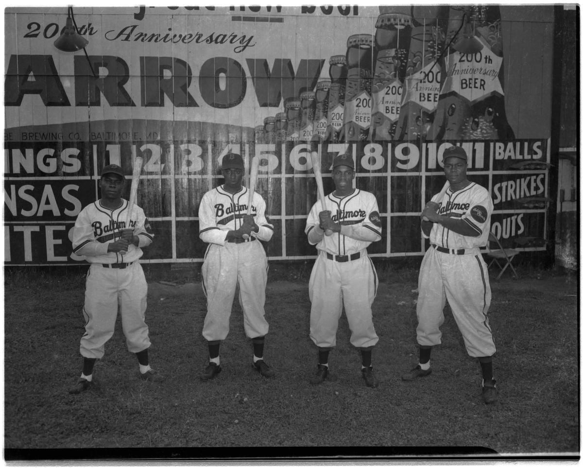 Black and white photo of four players holding baseball bats