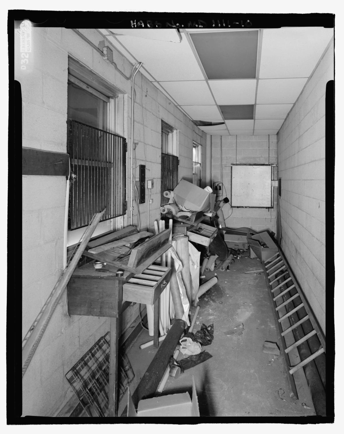 Narrow stadium corridor cluttered with discarded equipment and debris.