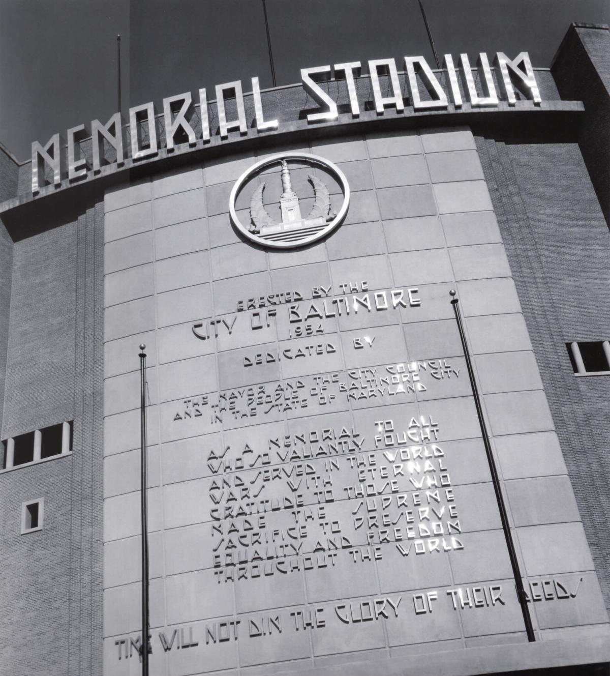 Close-up of the Memorial Stadium facade showing the dedication inscription and monument emblem.