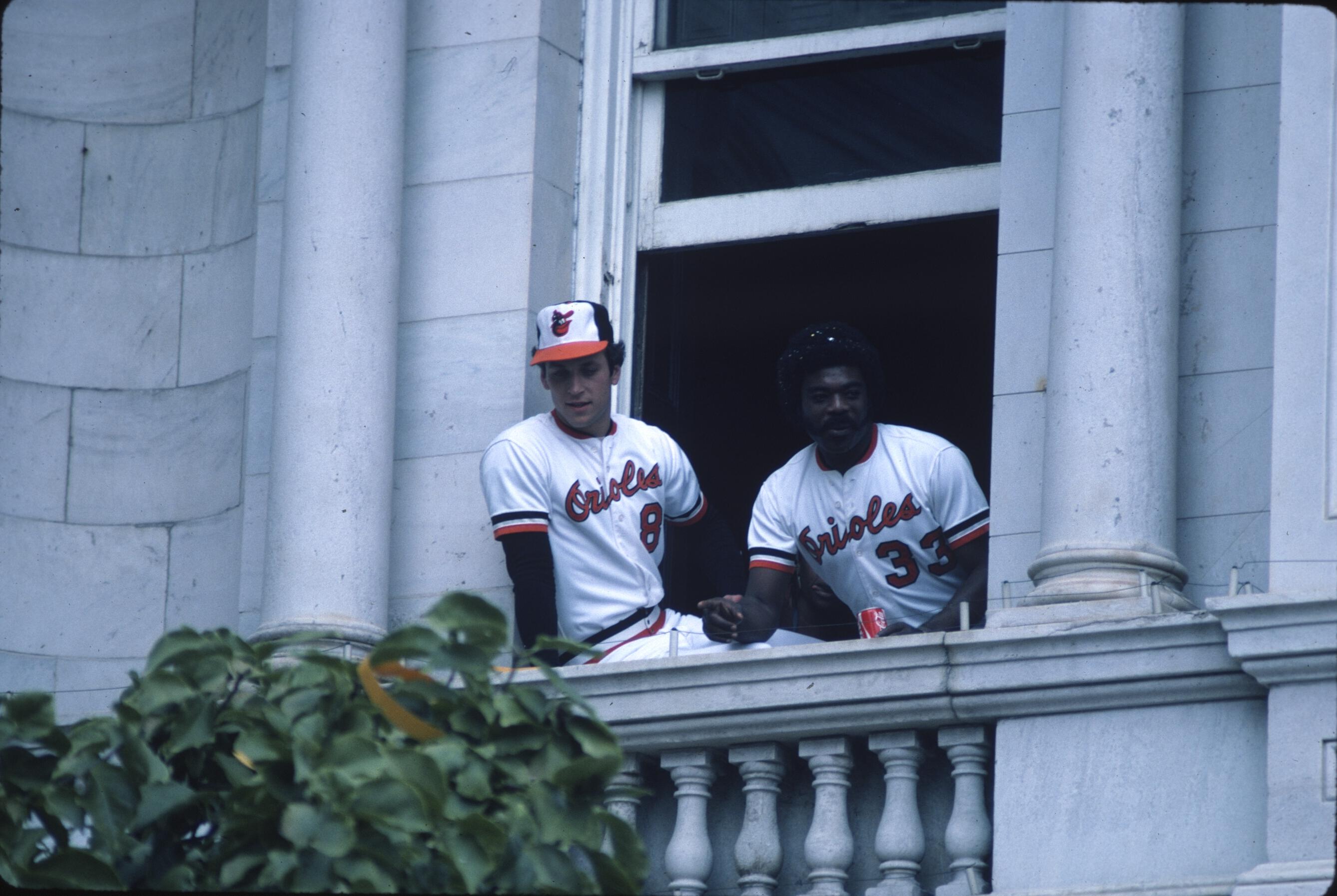 Two players lean out of a building window