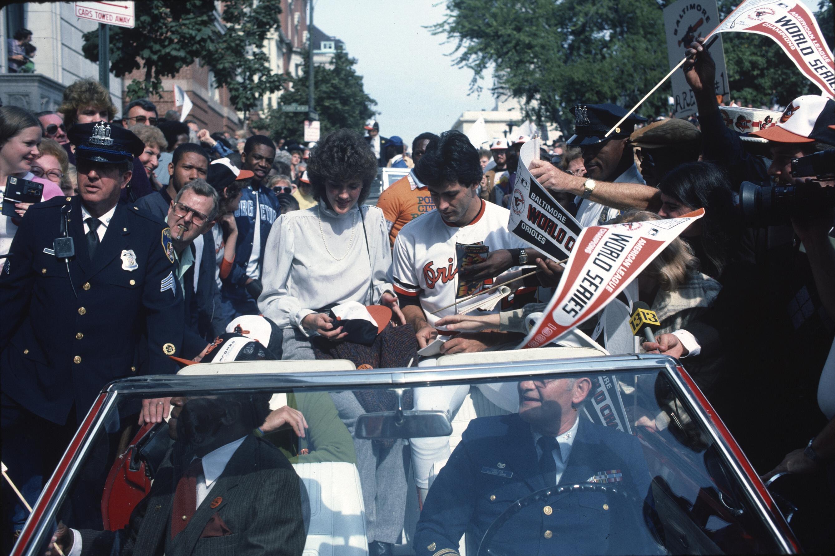 People ride in a convertible through crowds of fans