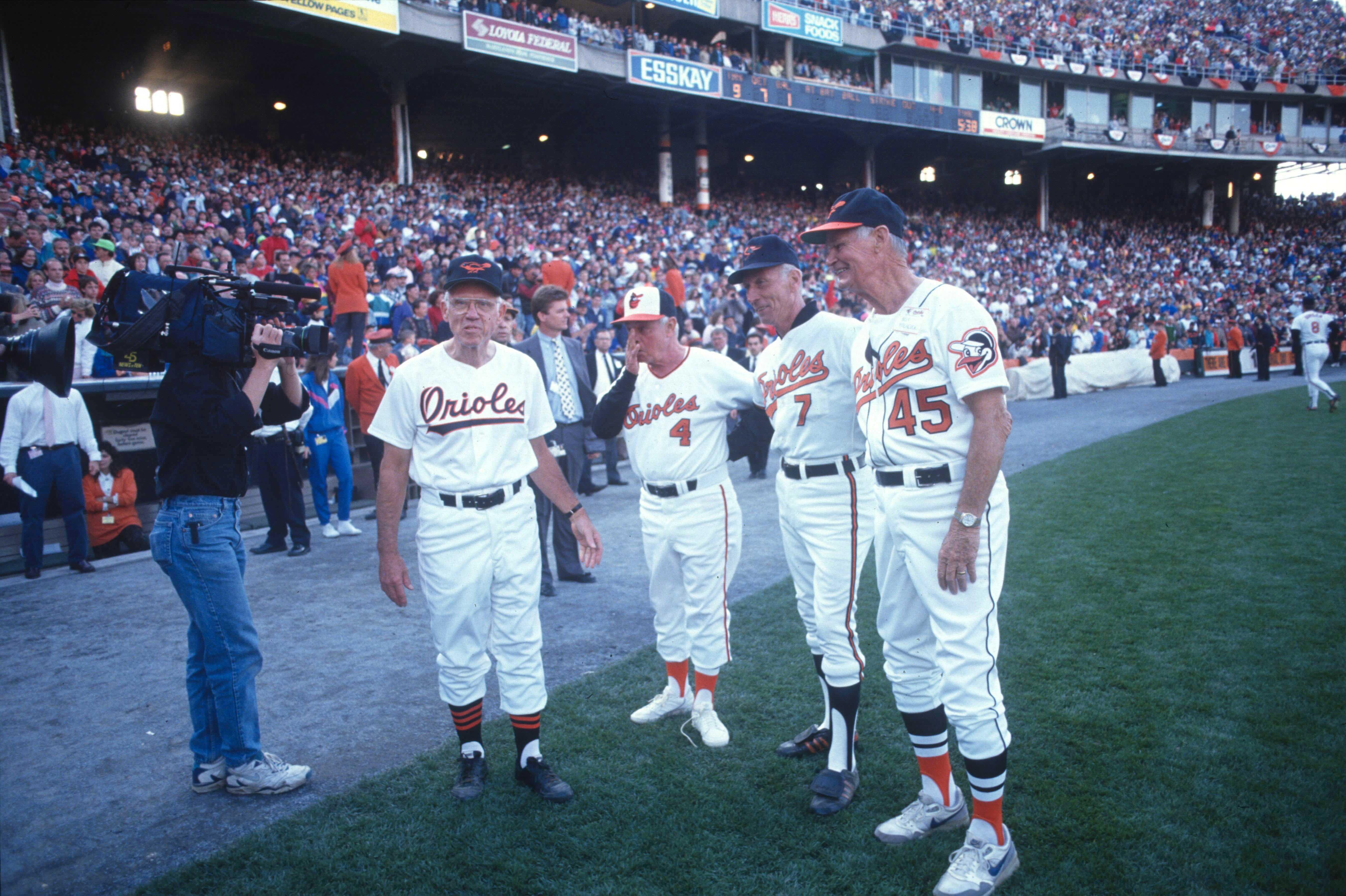 Four retired Orioles players stand together on the field