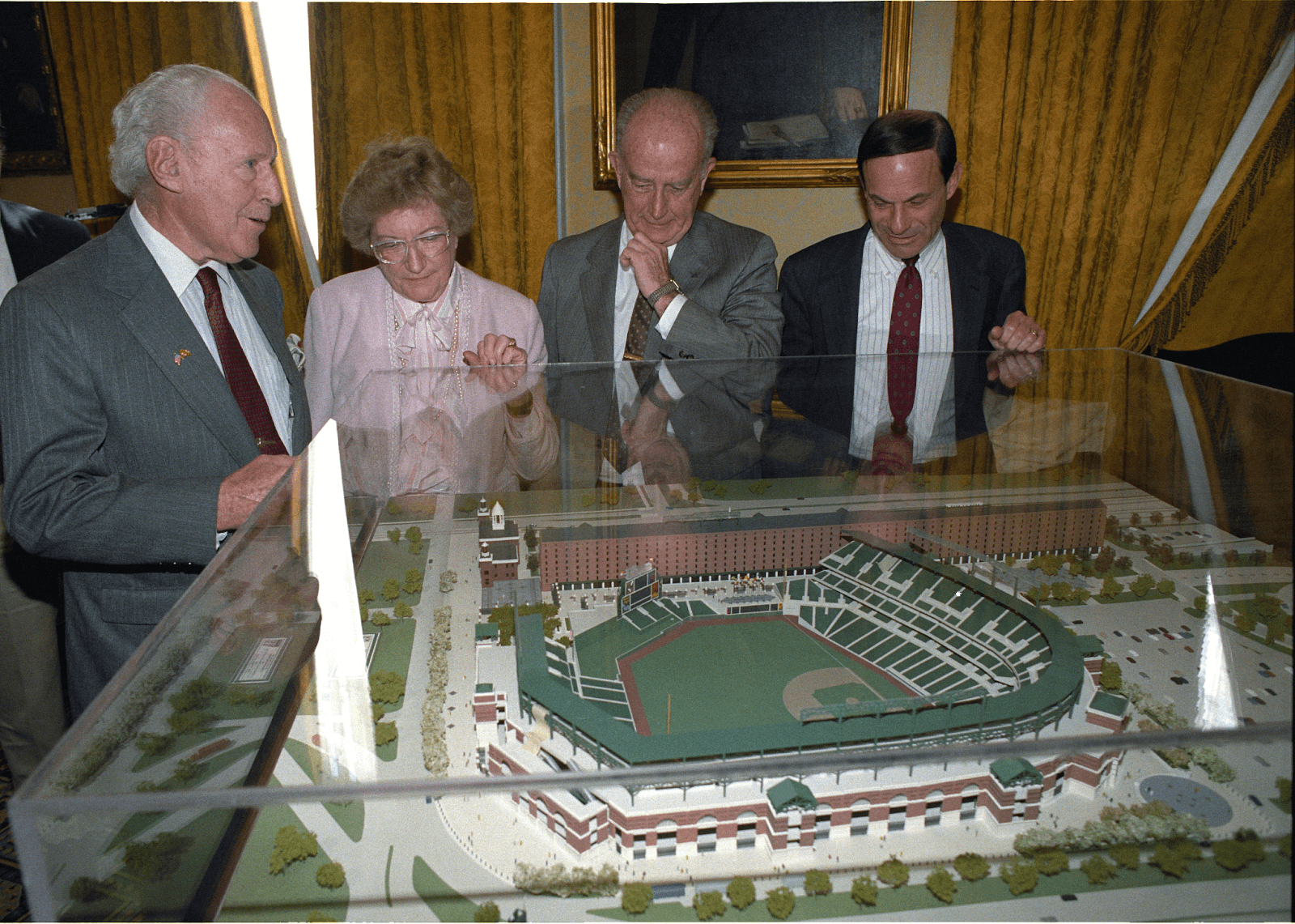 Officials examining a scale model of Camden Yards displayed inside a glass case.