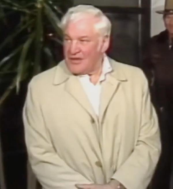Robert Irsay wearing a light yellow jacket and speaking during a press conference