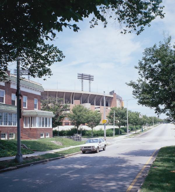 Trees in the foreground with Memorial Stadium along a street in the background
