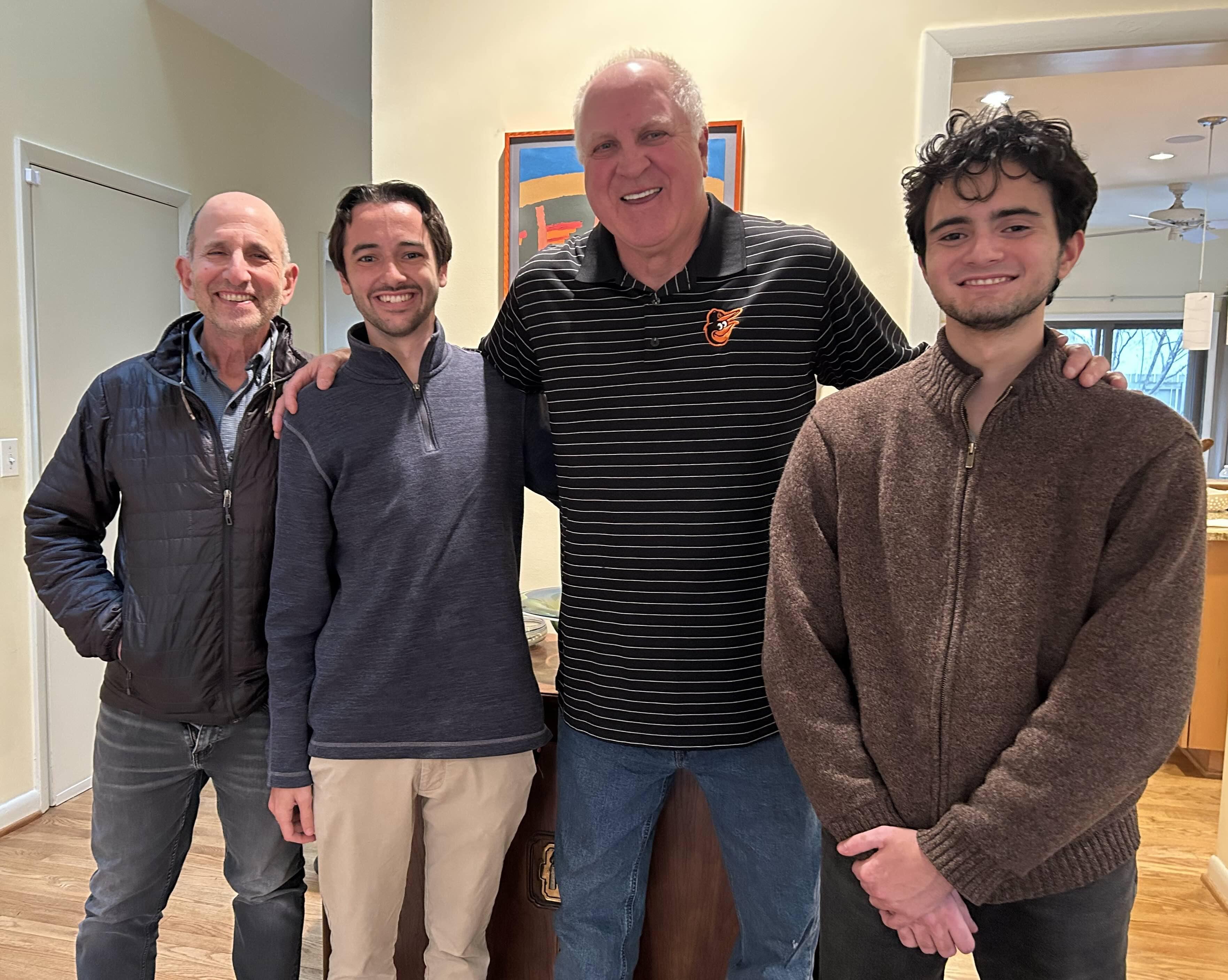 Four men standing together indoors posing for a photo.