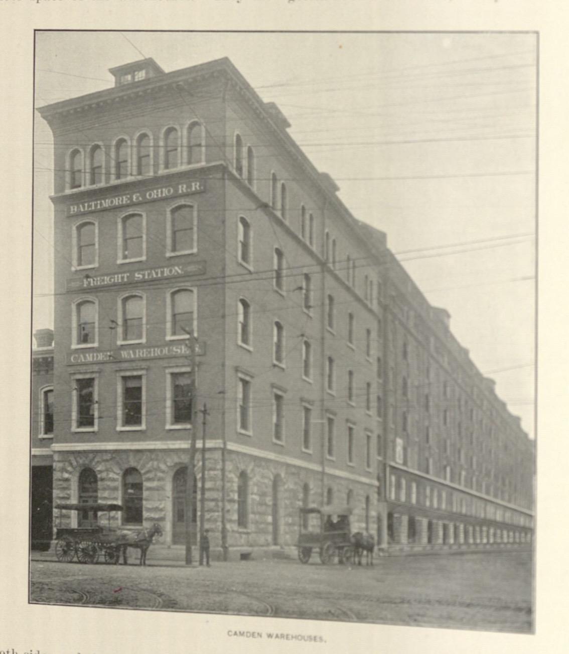 Black and white photo of a long brick warehouse with windows
