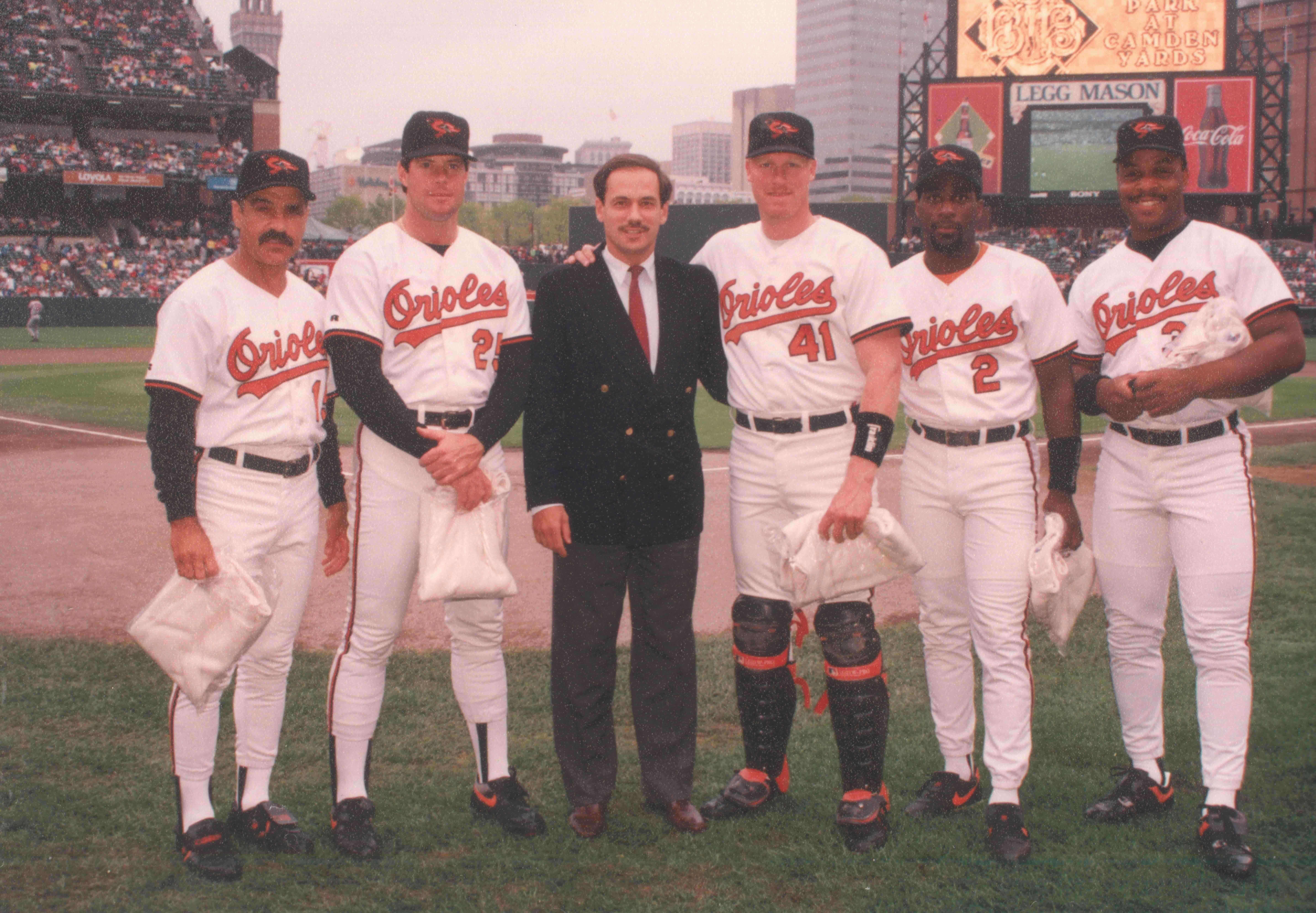Larry Lucchino stands on the field with several Orioles players