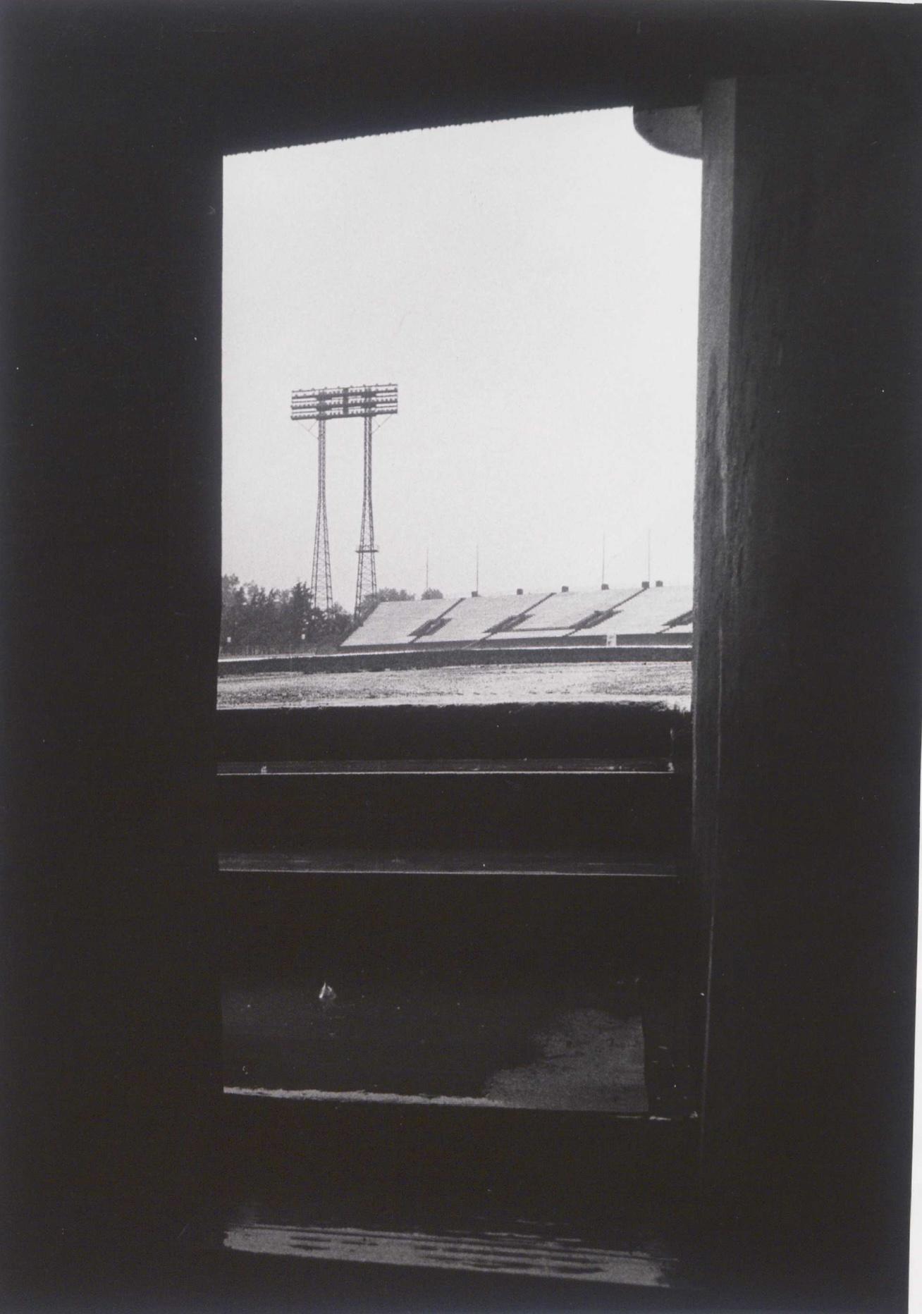 View of seating and a light tower seen through a dark stadium corridor or tunnel.