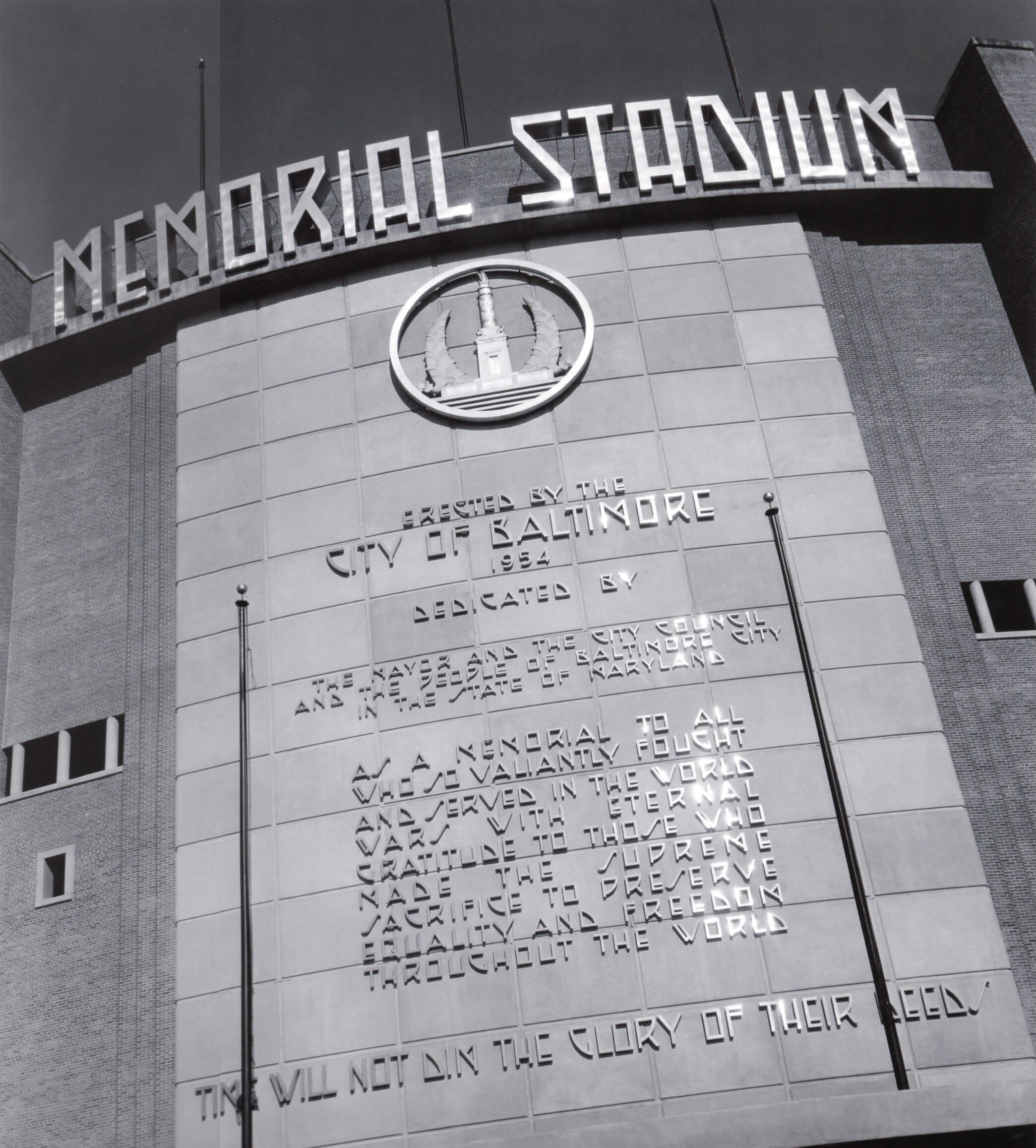 Close-up of the Memorial Stadium facade showing the dedication inscription and monument emblem.