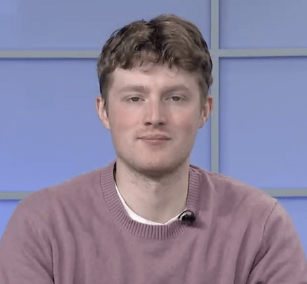 Young adult man in a pink shirt and in a blue media room